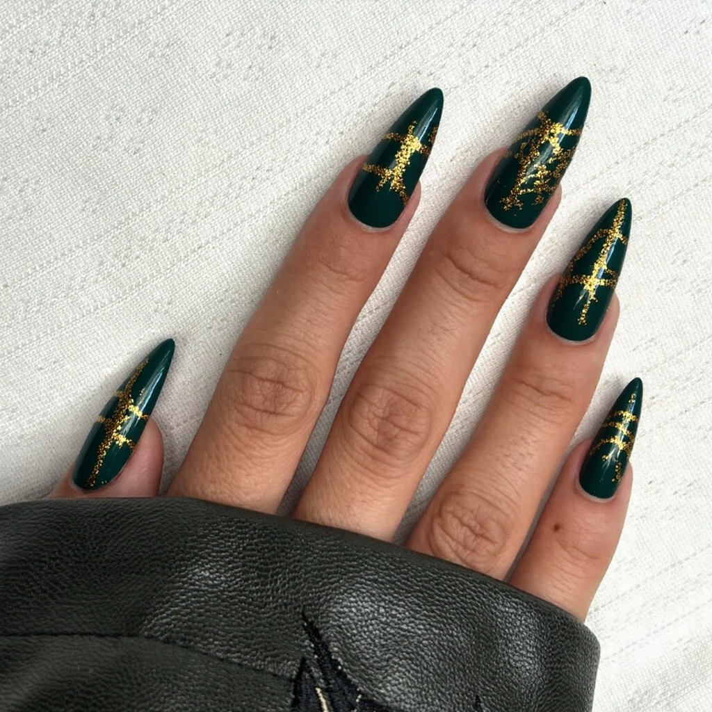 Long stiletto nails in a deep green with gold foil stripes, perfect for a glamorous holiday party.
