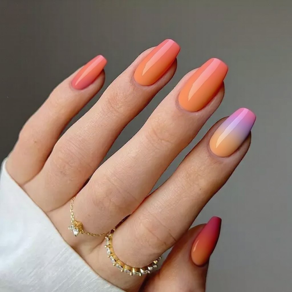 Medium stiletto nails featuring an ombre transition from coral to peach, adding a vibrant touch to my style.