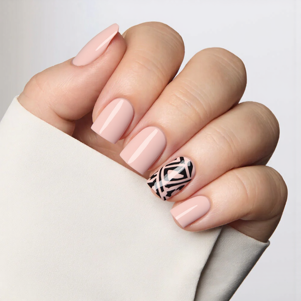 Short square nails in pale pink, with one accent nail featuring a simple geometric pattern in black.