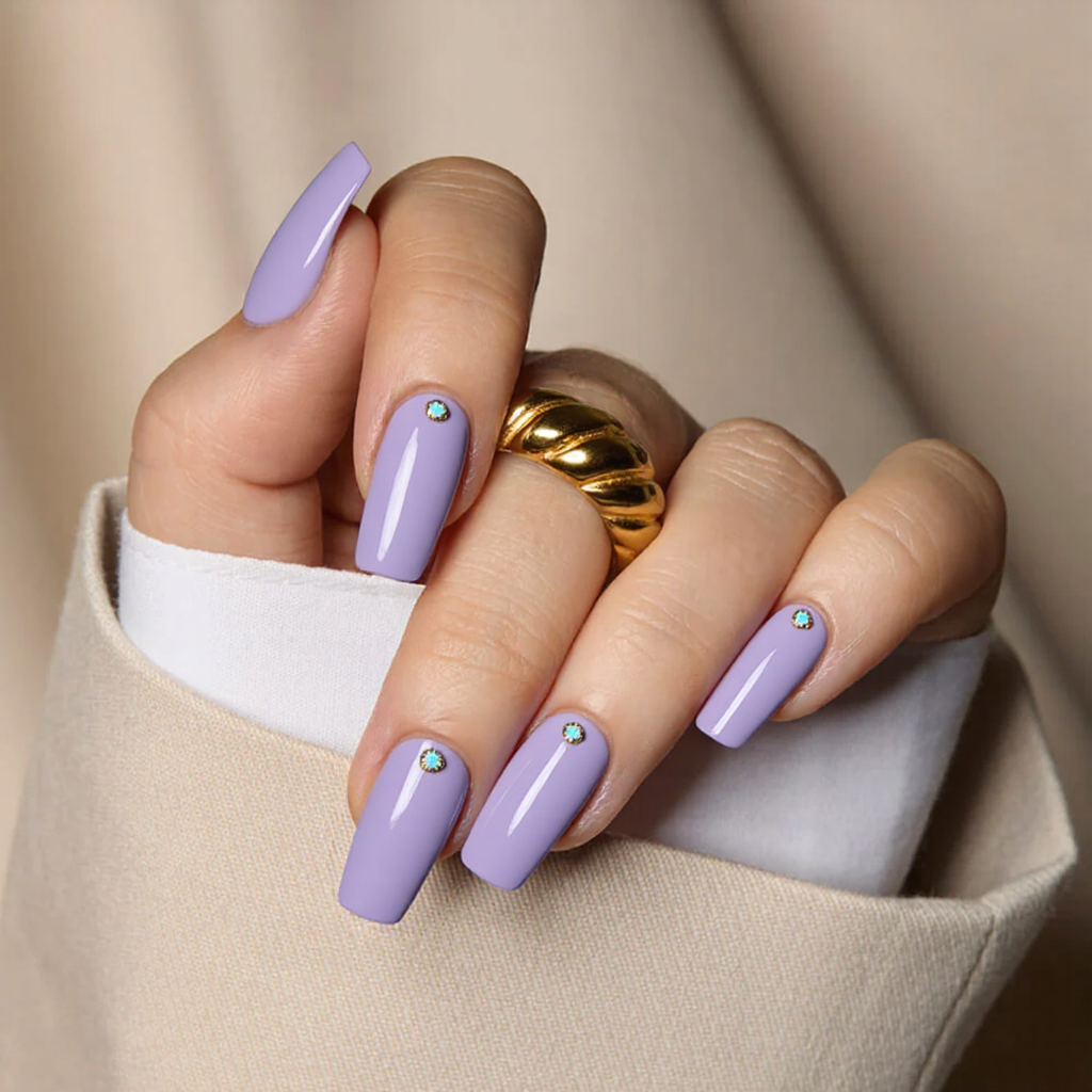 Medium square nails in a pastel violet, each with a small opal gemstone near the cuticle.