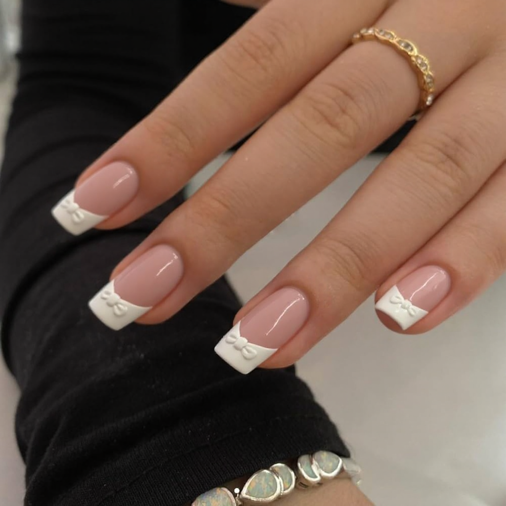 Short stiletto nails with a classic French tip, but each ring finger features a small delicate bow at the base.
