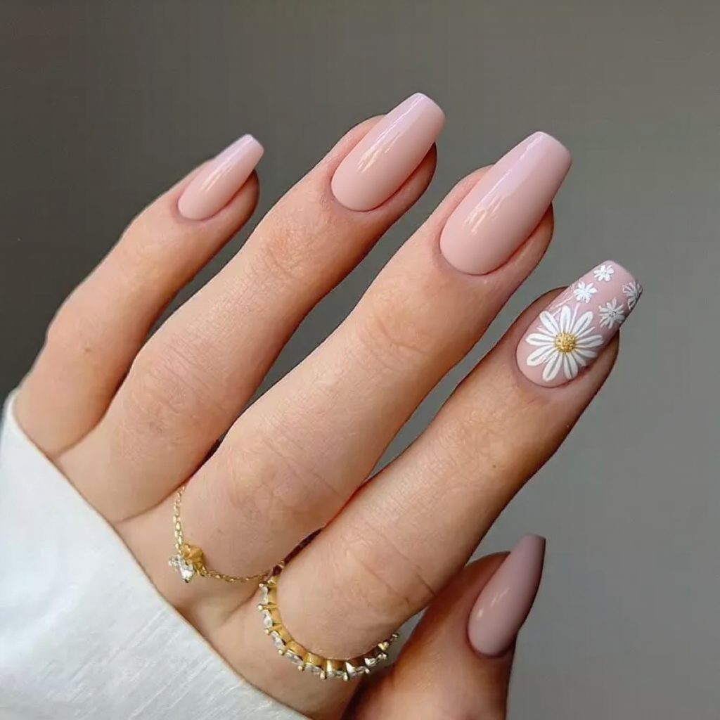 Medium stiletto nails in a soft blush pink, with hand-painted white floral accents on the ring fingers.