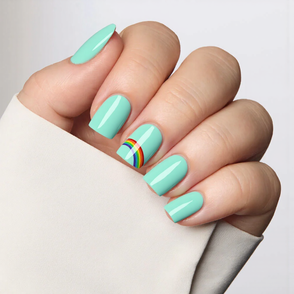 Short square nails in a bright mint shade with a small rainbow sticker on the ring finger.