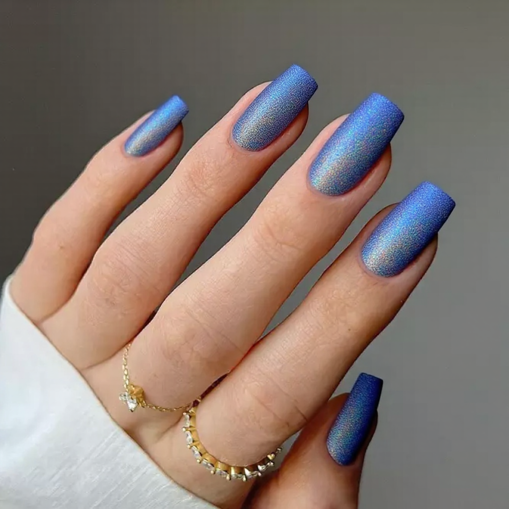 Medium stiletto nails in holographic blue, catching different shades under the light.