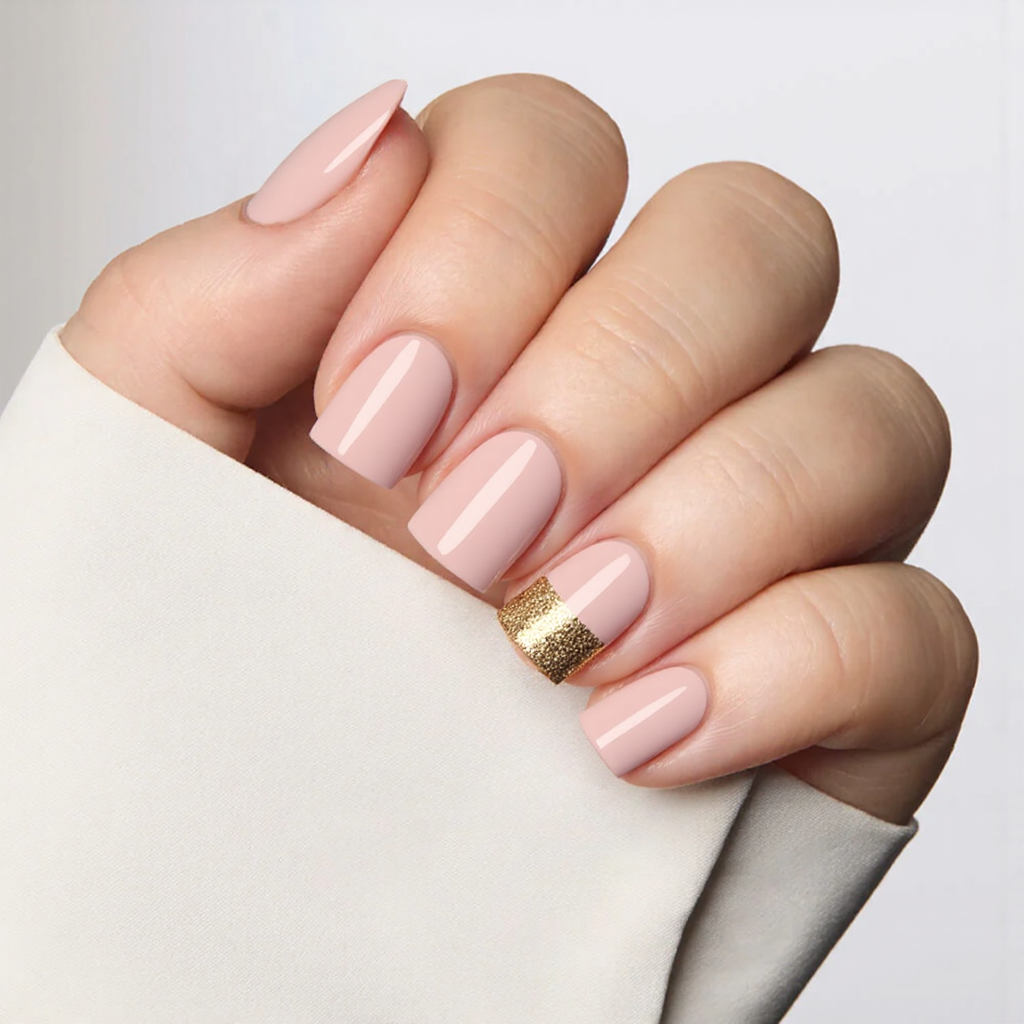 Short square nails in a pastel rosy hue, maybe with a gold glitter stripe across one accent nail.