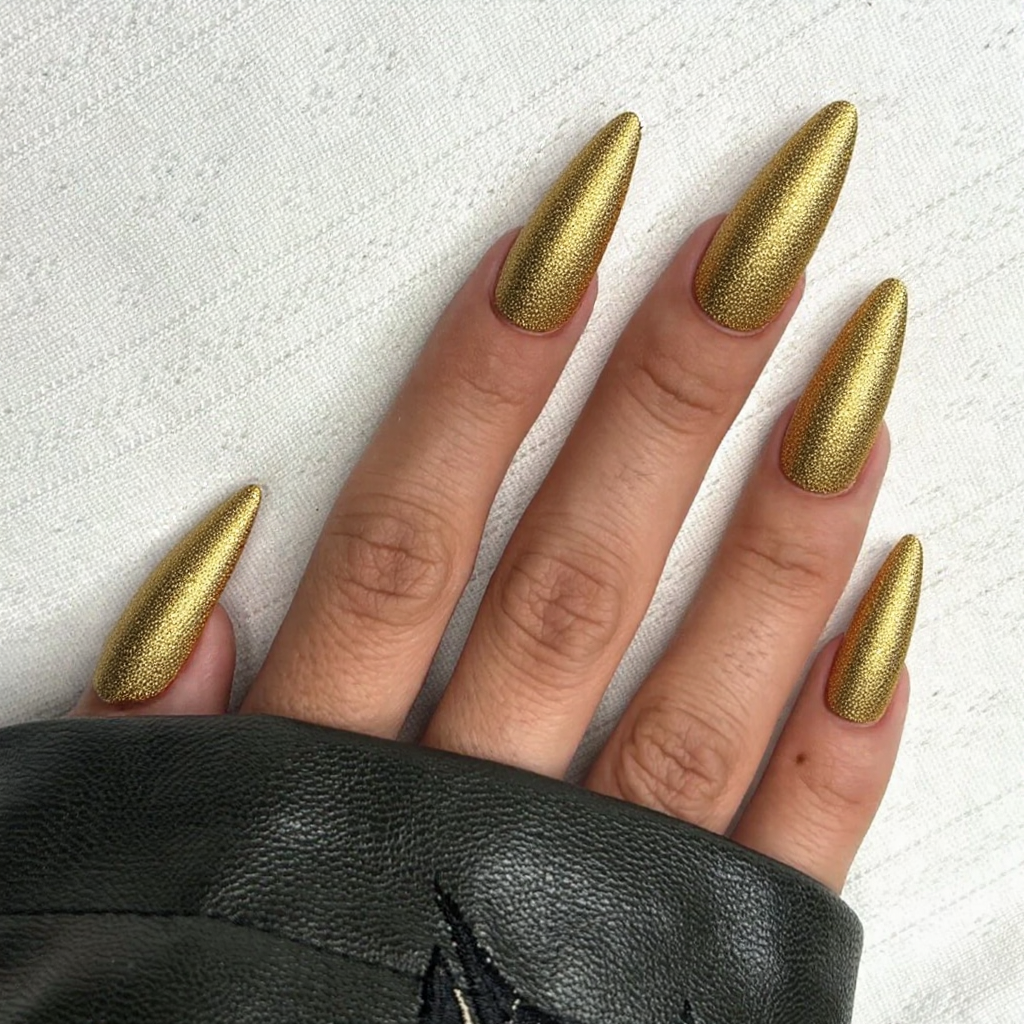 Long stiletto nails in a vibrant gold with subtle glitter, making a statement at holiday gatherings.