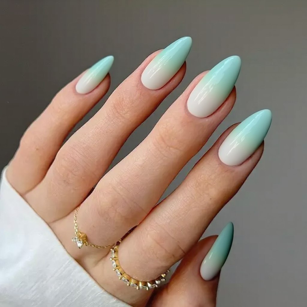 Medium stiletto nails featuring a playful ombre from mint green to white, adding a fresh touch to my nails.