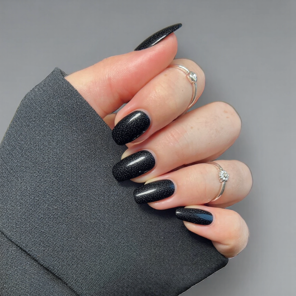 Short almond nails in black with a micro-glitter finish, perfect for a subtle sparkle.