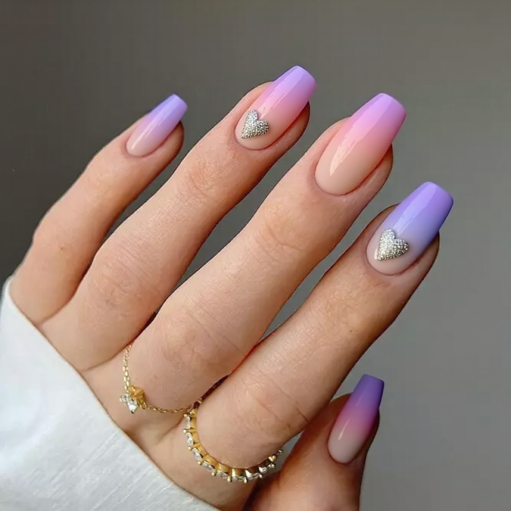 Medium stiletto nails in a sherbet-inspired ombre with a tiny glitter heart on each nail.