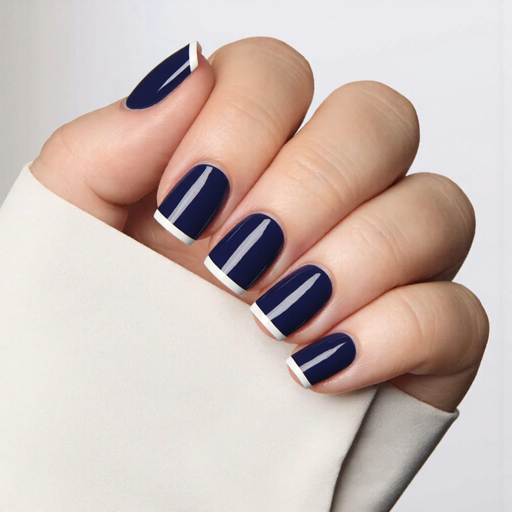 Short square nails painted in a glossy indigo, with a simple white stripe near the tips for a chic look.