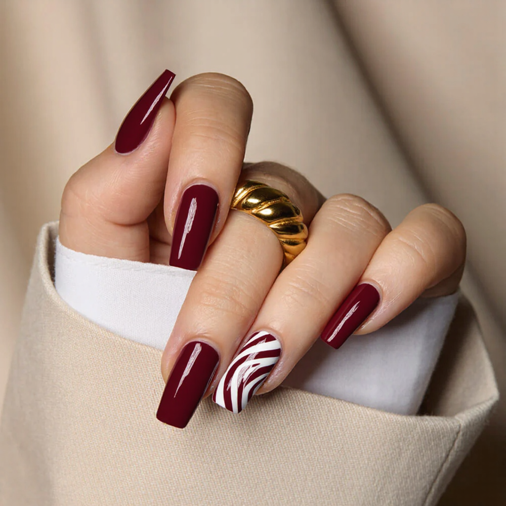 Medium square nails in a bold burgundy with white candy cane stripes for a playful Christmas manicure.