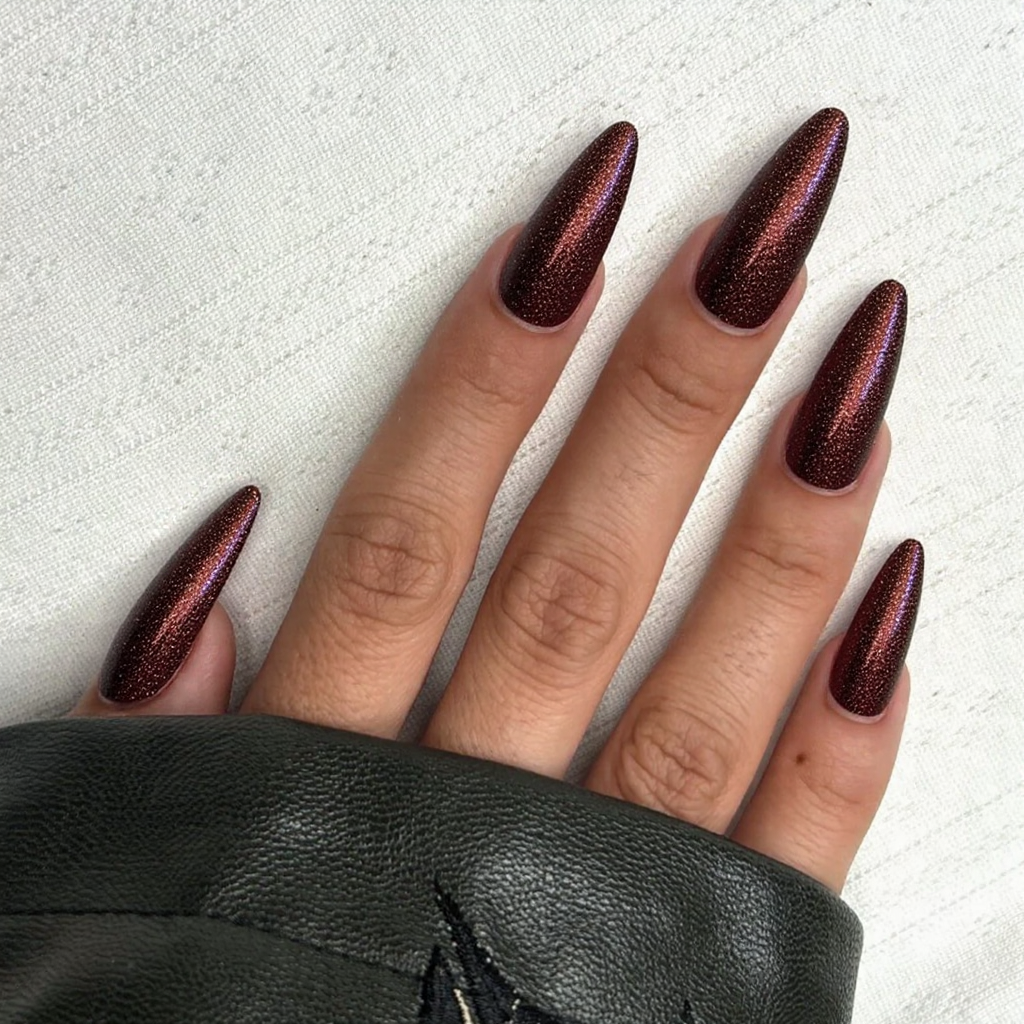 Long stiletto nails in a deep burgundy with gold glitter accents, ideal for a glamorous February evening.
