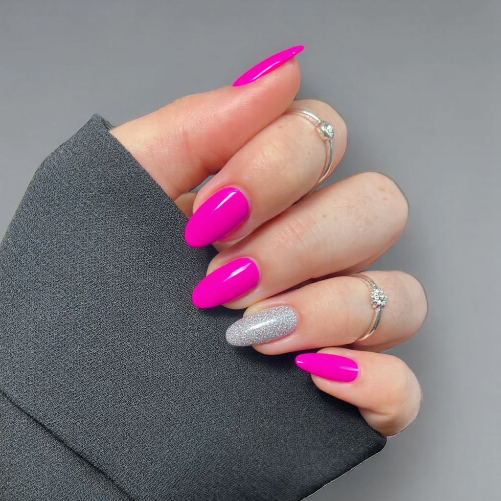 Short almond nails painted in a bright magenta with a single glitter accent nail to catch the light.