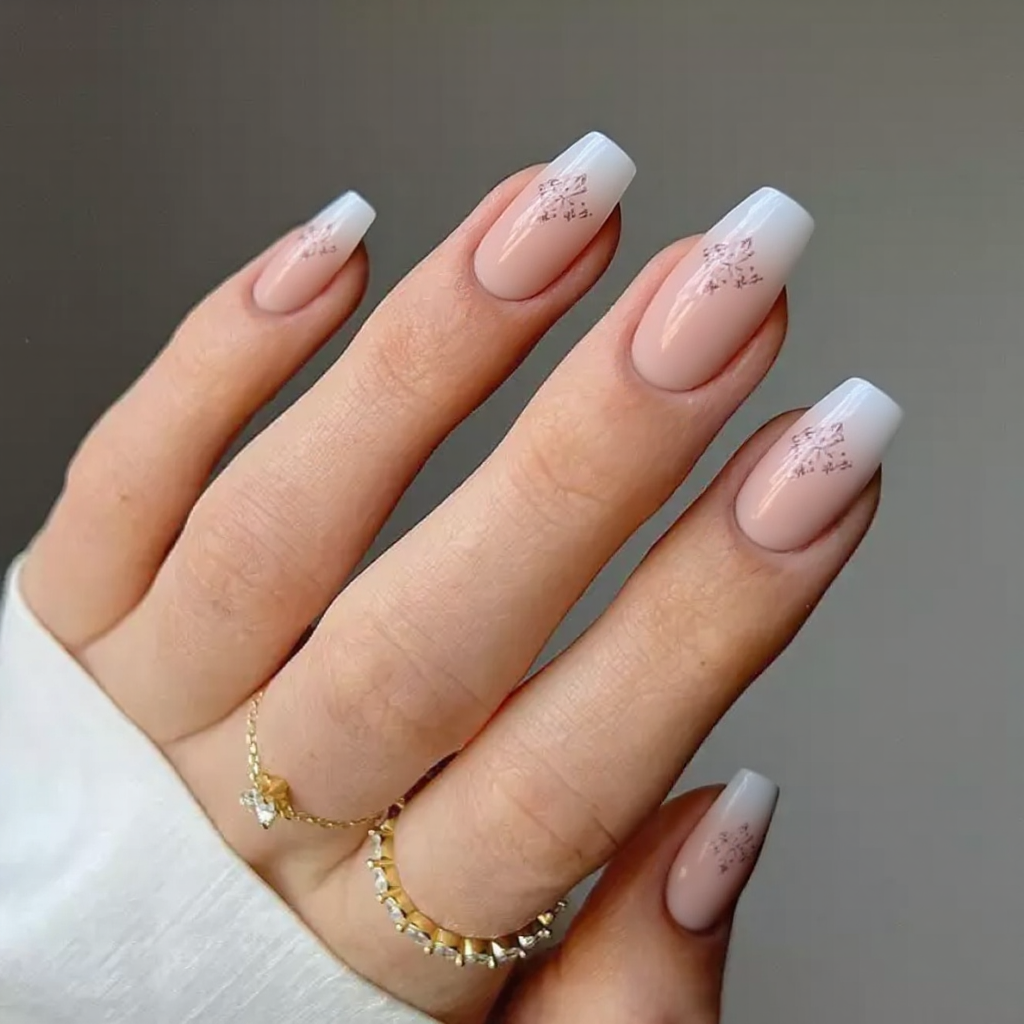 Medium stiletto nails in a French manicure, each ring finger featuring a small floral accent over the tip line.