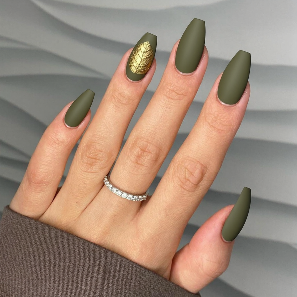 Long almond nails in a soft olive green with a matte finish and a single gold leaf accent for a subtle autumn touch.
