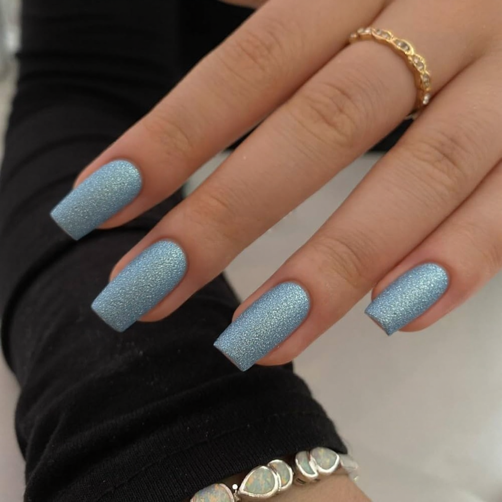 Short stiletto nails in a frosty blue with silver shimmer, perfect for a snowy holiday look.