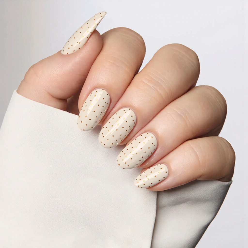Medium almond nails in a soft ivory with tiny gold dots, adding a touch of elegance for the holidays.