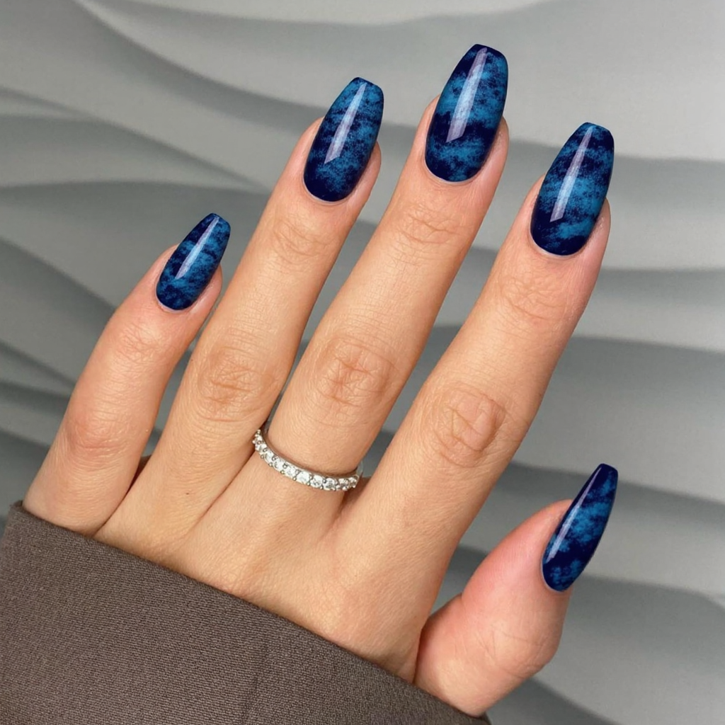 Long almond nails in navy with subtle brushstrokes of light blue to create a watercolor effect.