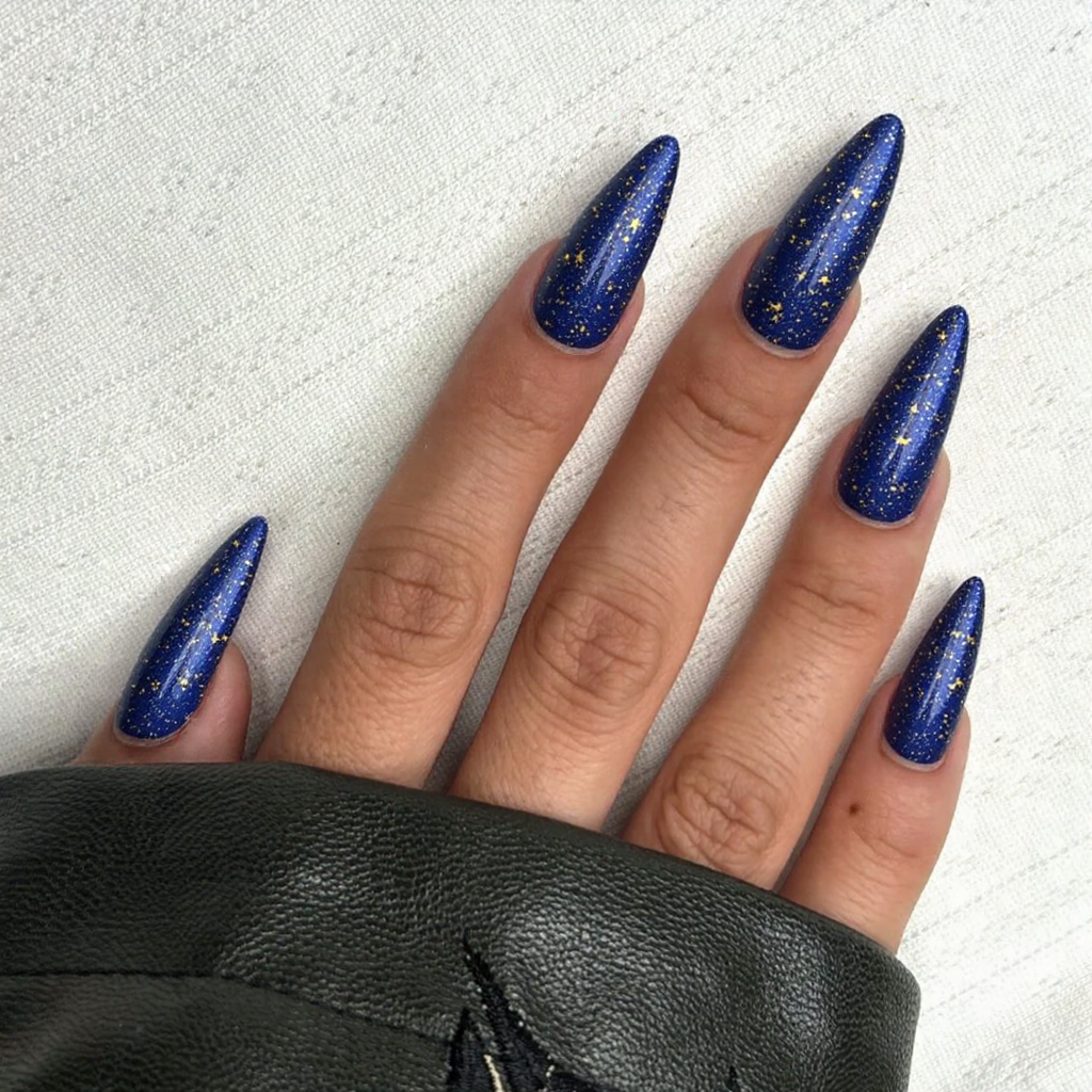Give me long stiletto nails featuring a galaxy-themed nail art design with stars and sparkles.
