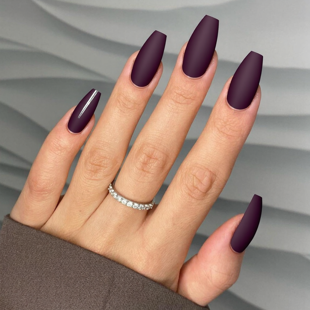 Long almond nails in a deep plum color, with a matte finish and a thin vertical metallic line on one accent nail.