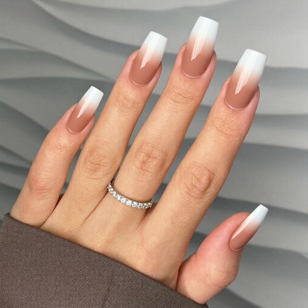 Long almond nails with a French tip that transitions from white to a metallic rose gold.