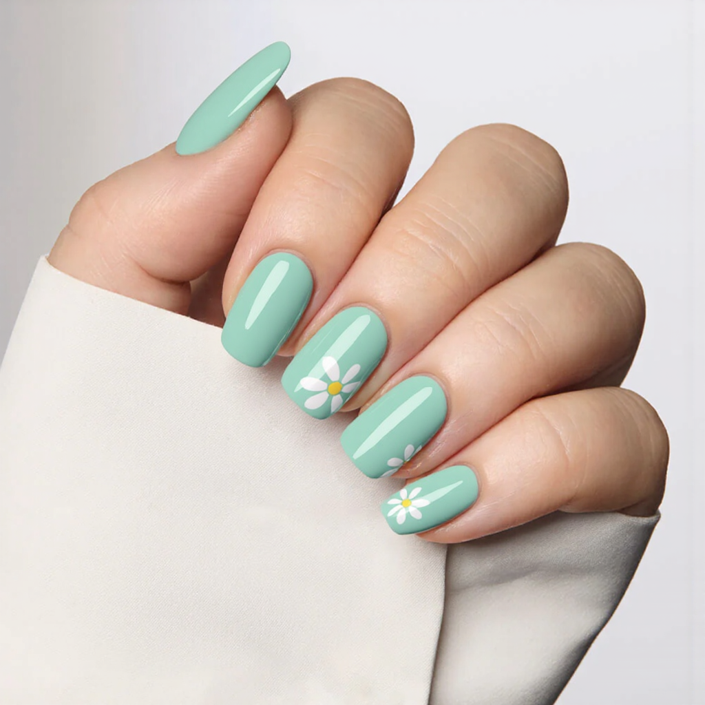 Medium almond nails in a seafoam green, each accented with a minimal white daisy on the ring finger.