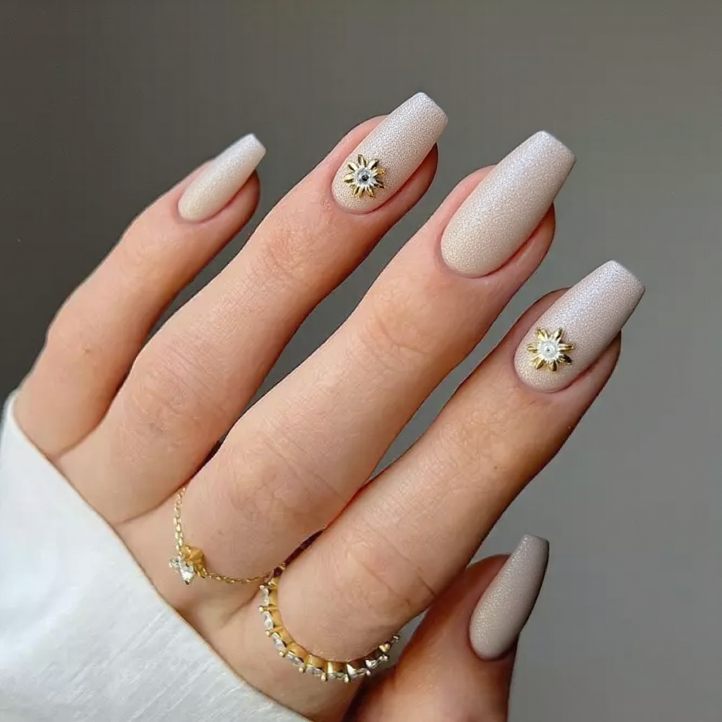 Medium stiletto nails in an ivory shimmer, each ring finger featuring a subtle 3D flower accent.