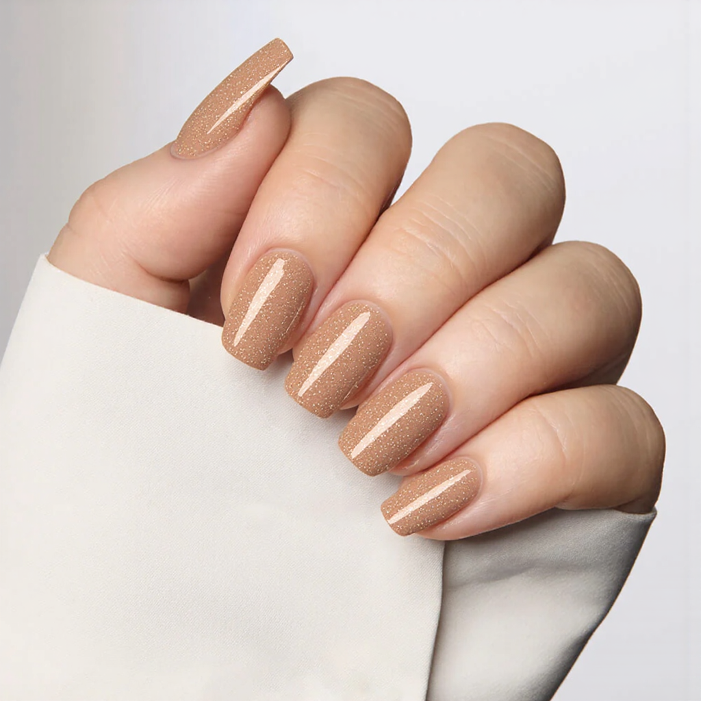 Medium almond nails in a translucent nude with fine gold flakes sprinkled near the tips.