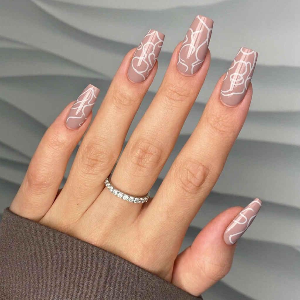 Long almond nails in a soft dusty rose, each with an abstract white swirl design for interest.