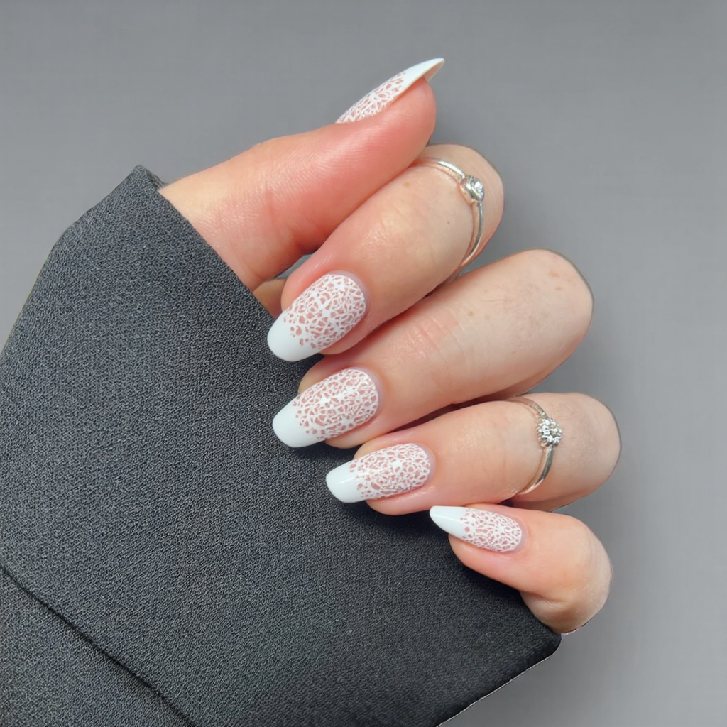 Short almond nails with a neat, thin white French tip and a delicate lace pattern on one accent nail.