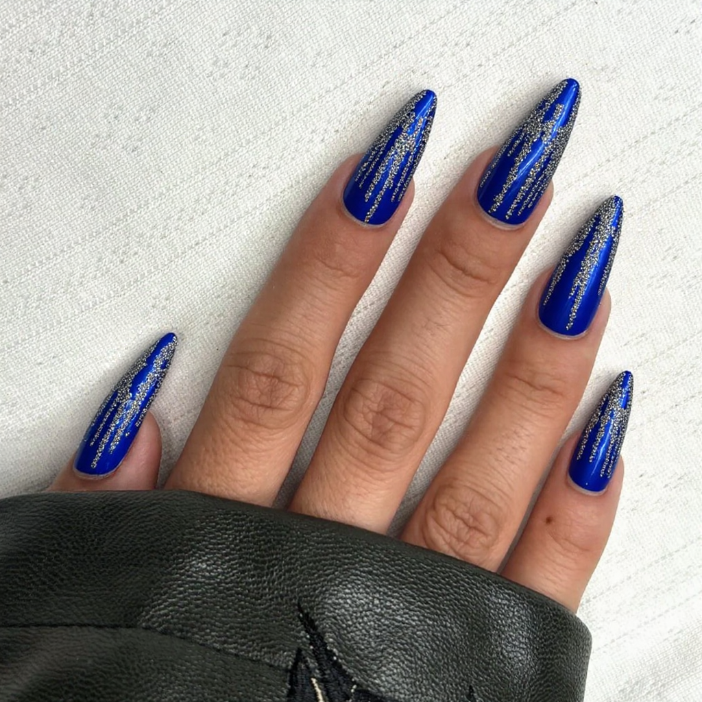 Long stiletto nails in a cobalt blue with silver glitter outlines on each nail to mimic icicles.