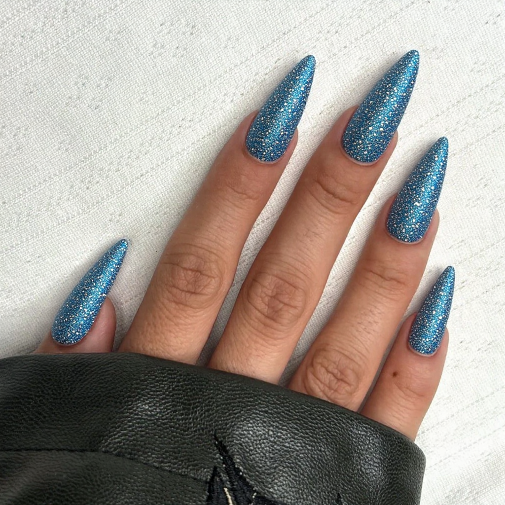 Long stiletto nails in a sparkling blue with silver rhinestones, capturing the essence of winter wonderlands.
