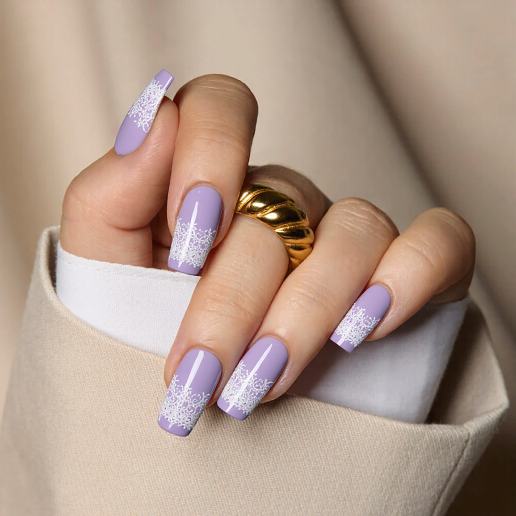 Medium square nails in pastel purple with a white lace-like pattern on the tips for a delicate spring design.