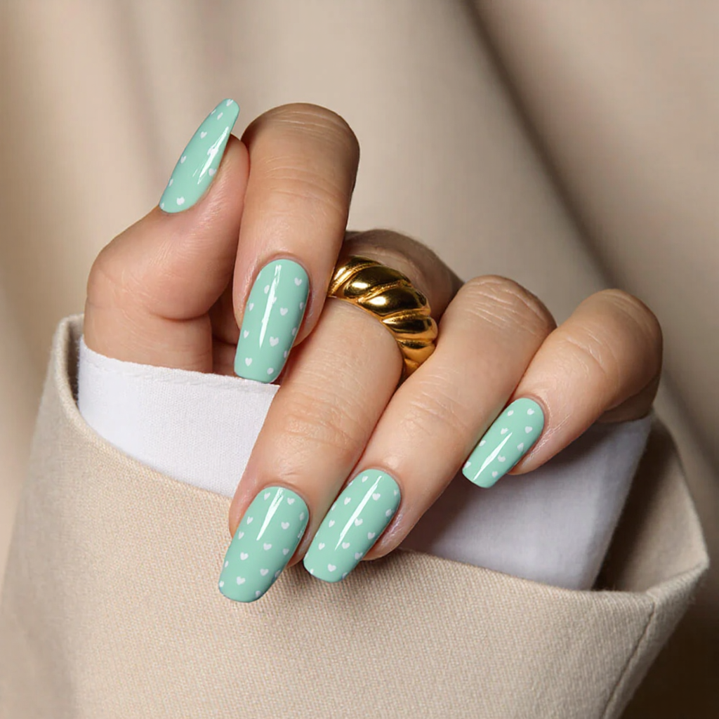 Medium square nails in a pastel mint green with tiny white hearts for a fresh and playful February manicure.
