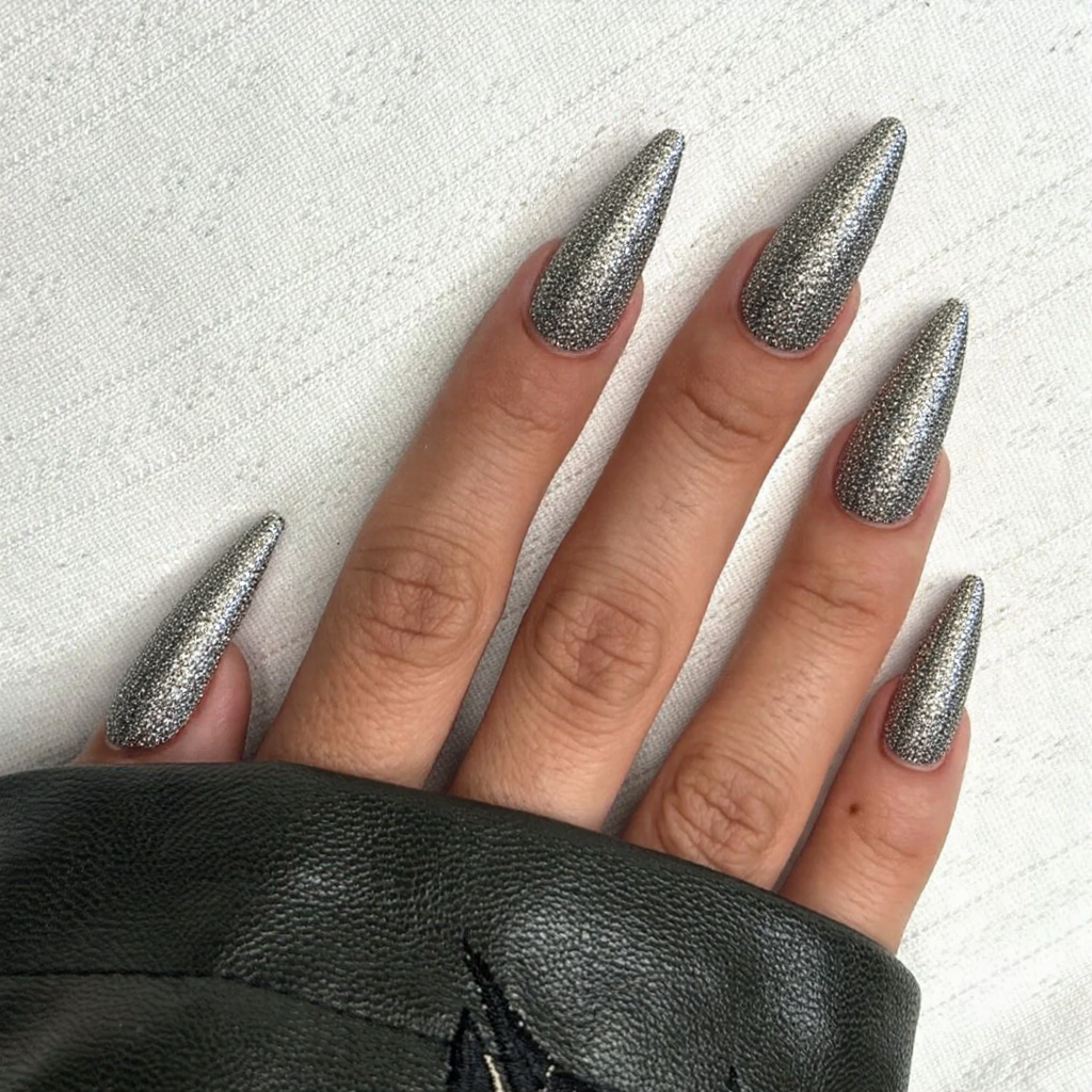 Long stiletto nails adorned with metallic stripes and studs for an edgy, runway-inspired nail art look.