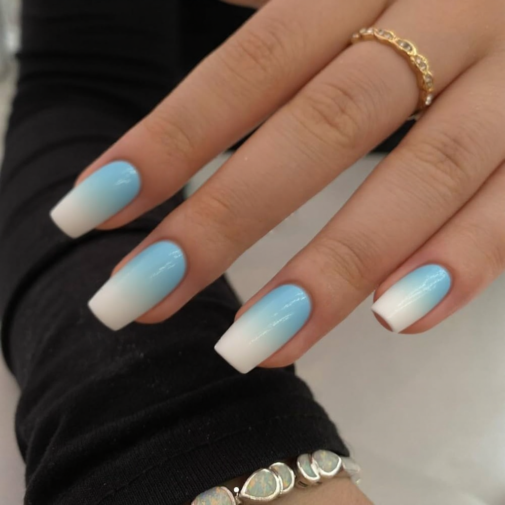 Short stiletto nails in a pastel blue ombre fading to white, perfect for a light, airy spring feel.