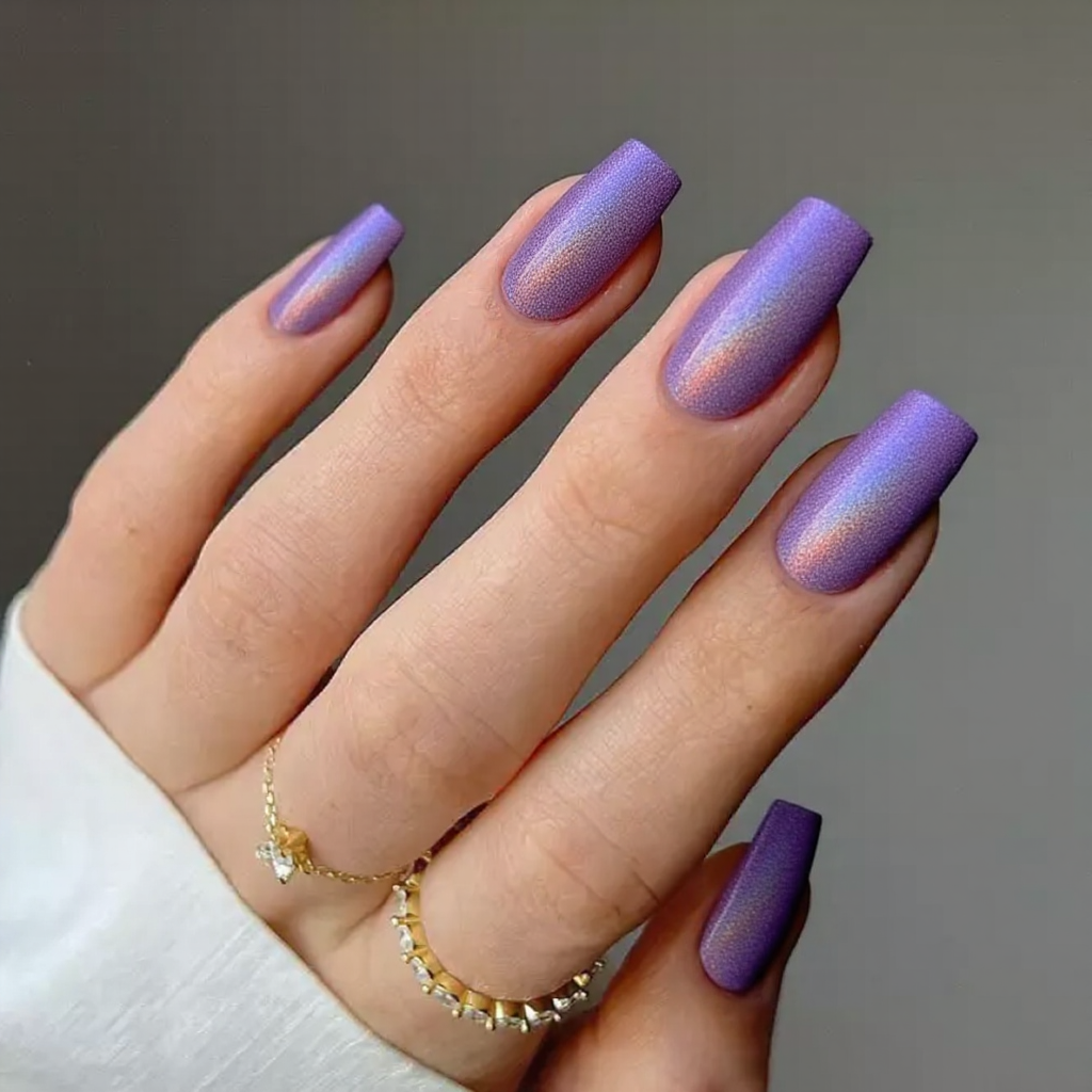 Medium stiletto nails in a holographic purple, catching different rainbow hues under the light.