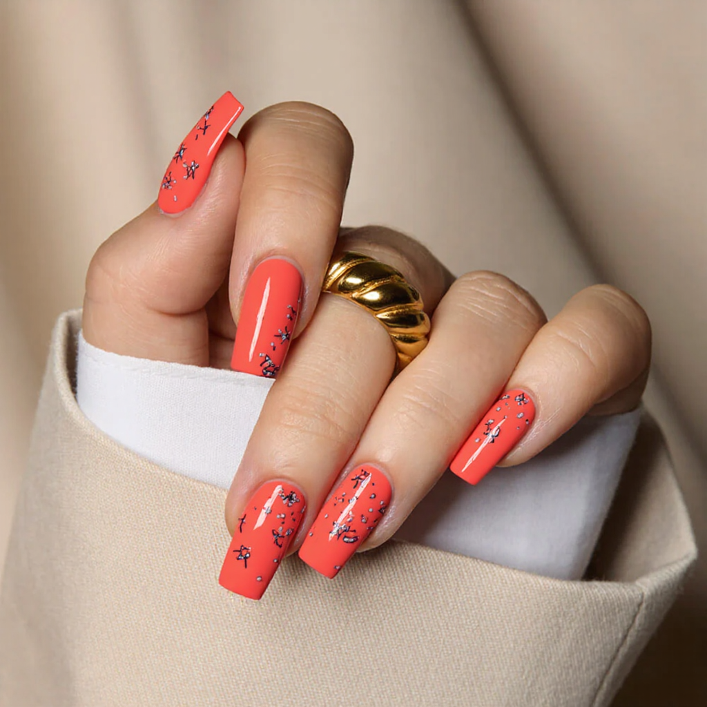 Medium square nails in a bright coral with tiny flip-flop designs for a playful vacation style.