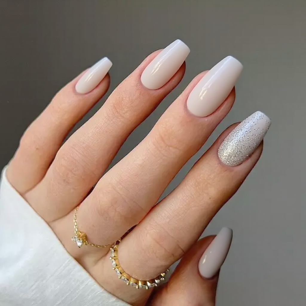 Medium stiletto nails in a sheer milky white, featuring small silver flakes on the ring finger to draw attention to the ring.
