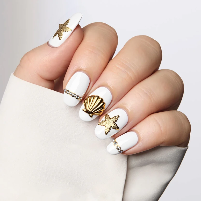 Nails designed in a classic almond shape featuring a pristine white French tip that elegantly curves along the edge. At the apex of the French tip, delicate golden snowflake stars are placed, adding a touch of winter charm and luxury to the look. Each nail is lined along the base with tiny, shimmering gems that catch the light beautifully, enhancing the overall glam of the design. One accent nail is adorned with a 3D seashell that showcases fine detailing, intricate textures, and a glossy finish, giving it an organic and playful touch. The remaining nails maintain a clean, polished finish, striking a balance between simplicity and elegance. The overall design is hyper-realistic with a refined aesthetic, making it basic yet irresistibly cute.