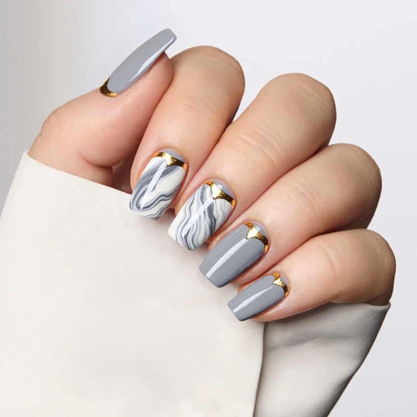 For your modern and edgy nail design, envision a sleek and sophisticated look featuring a soft gray base color on all nails, providing a minimalist backdrop. On the middle and ring fingers, a swirling marble effect in shades of white and light gray creates a fluid, organic feel, while delicate gold foil accents are strategically placed along the edges of the marble patterns, adding a touch of luxury and shine. The remaining nails maintain the solid gray base, ensuring a balanced and harmonious appearance. A glossy finish enhances the overall elegance of the design, perfectly suited for the almond shape and medium size of your nails, keeping the look refined yet contemporary.