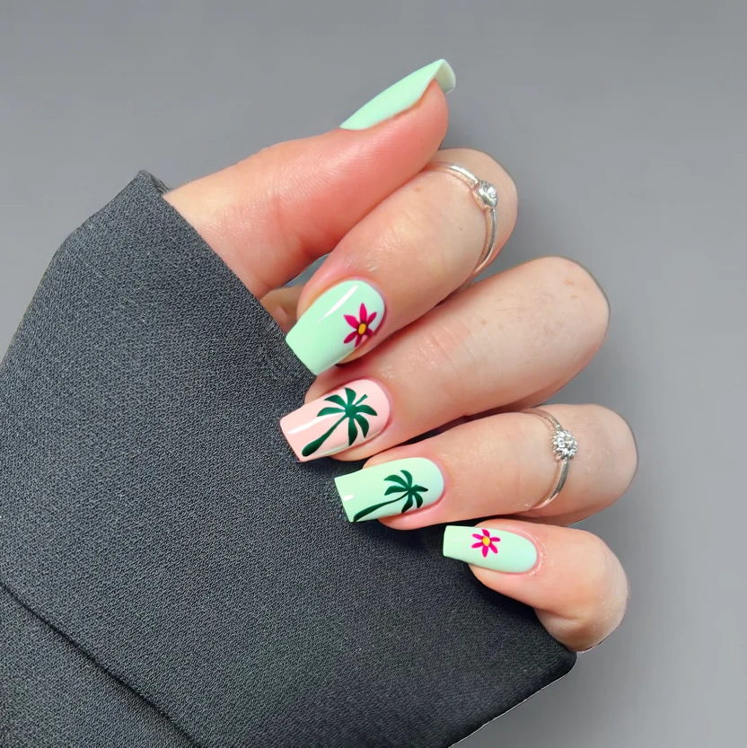 A bright and fun tropical nail design perfect for a beach vacation, featuring delicate palm leaves and hibiscus flowers. The design includes soft pastel colors like mint green and blush pink as the base color for all nails. On the ring fingers, there are minimalistic hand-painted palm leaves in a subtle darker green, accompanied by small, simplified hibiscus flowers in soft pink. A single, tiny pineapple accent is placed on one of the index fingers, complementing the tropical theme. The remaining nails have a plain pastel base with a glossy finish to enhance their vibrancy while maintaining an elegant look. The design is tailored for medium-length almond-shaped nails, ensuring a fresh and feminine appearance.
