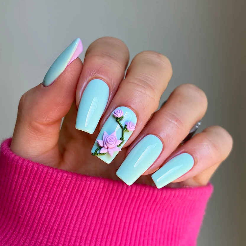 Long square-shaped nails featuring a delicate, ethereal color palette of soft pastel blues and aquamarine, reminiscent of serene water. The base color is applied uniformly across most nails, providing a calm backdrop. On the ring and middle fingers, a minimal yet intricate 3D lotus flower is elegantly placed at the cuticles, crafted in shades of pale pink with subtle shimmers that catch the light. Accompanying the lotus, dainty, stylized roses in soft lavender are positioned around, each adorned with a hint of iridescent sparkle to enhance their lifelike appearance. The finish is a glossy sheen that complements the water theme, ensuring the entire look is feminine, harmonious, and visually striking against the elongated square shape.