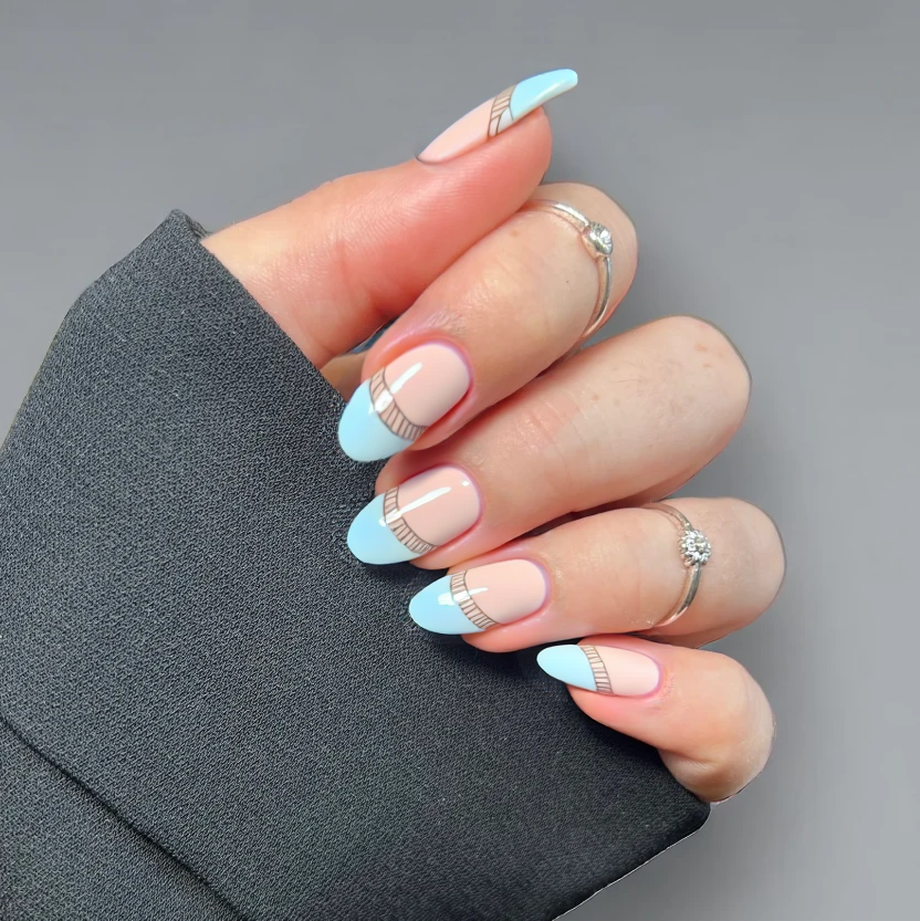 Nails adorned in a sophisticated twist on a classic French manicure, featuring a delicate base coat of pale sand beige to evoke a serene beach vibe. The tips elegantly painted in a soft, pastel ocean blue, capturing the tranquil hues of the sea. To complement the beach theme, minimalistic wave patterns in a subtle engraved style gracefully flow along the edges of the blue tips on the ring fingers, while the rest of the nails remain elegantly simple. A glossy finish elevates the formal look, ensuring each almond-shaped nail radiates refinement and charm.