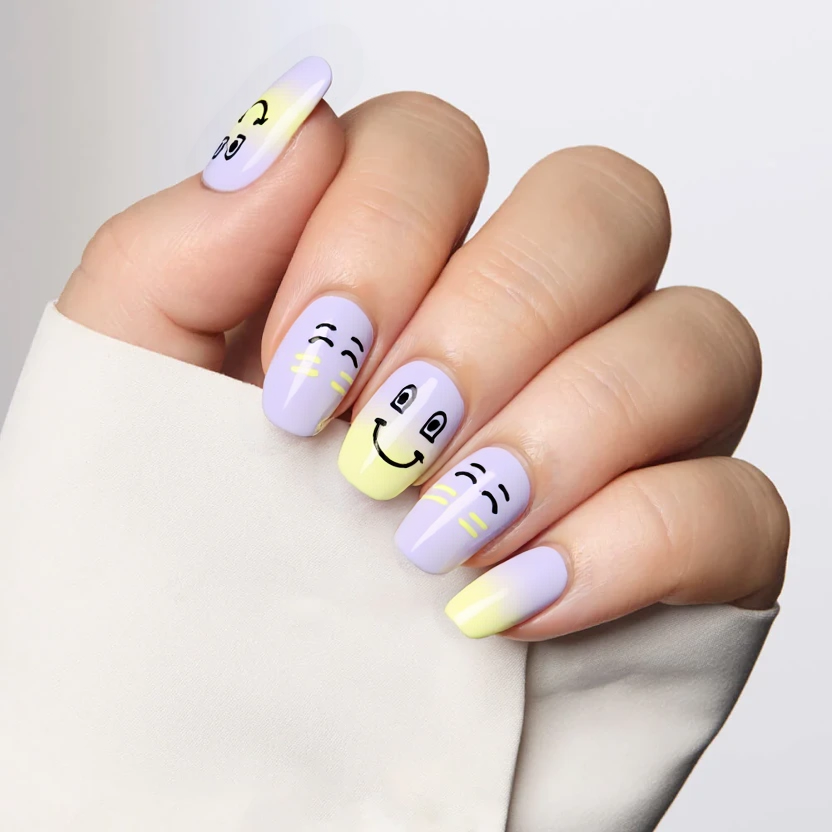 Nails are painted with a soft pastel lavender base on all but three of the almond-shaped medium nails, creating a serene backdrop for the fun designs. The two accent nails feature a smooth gradient transitioning from pastel purple at the cuticle to a pale, sunny yellow at the tips, evoking an artistic vibe. Delicate, playful graphics include tiny cartoonish winking eyes and exaggerated smiley faces in subtle black, placed near the cuticles of these accent nails to reflect the upbeat, quirky essence of the song. Sprinkled across the remaining nails are small heart shapes in a soft pastel pink, adding a cute, rebellious touch. To enhance the overall look, a fine line of holographic glitter graces the tips of all nails, offering a subtle shimmer. The overall finish is glossy, providing a polished, elegant look while maintaining a fun, whimsical feel that perfectly balances the light-hearted themes of the design.
