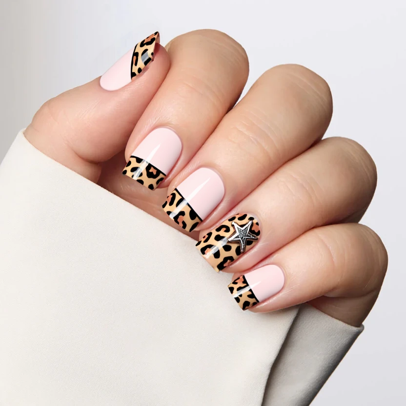 Nails featuring a soft pastel pink base color, creating a delicate and feminine look. The tips of the nails are adorned with a subtle cheetah print design, incorporating soft, muted browns and tans to maintain an elegant vibe. On the ring fingers, a charming star charm is attached, adding a touch of whimsical flair. The other nails display a refined airbrushed effect in pink alongside the cheetah print French tips, enhancing the cohesive theme. The design is complemented by a glossy finish, which adds shine and depth, perfectly suited for the short square shape, ensuring a balanced and chic aesthetic.