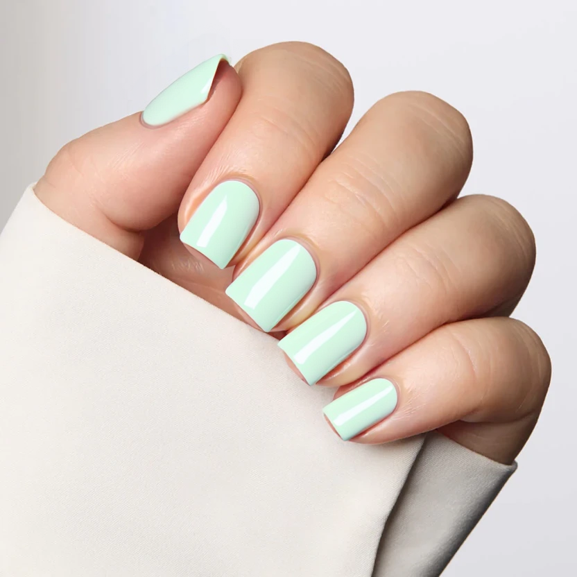 Nails coated in a natural builder gel, providing a smooth, glossy base that enhances the nails' natural beauty. A rounded French tip in a very light summer green delicately graces the top edge, offering a fresh and subtle contrast against the clear base. The minimalist design perfectly suits the short square shape, exuding an elegant and understated aesthetic. Each nail remains simple and refined, reflecting a modern take on the classic French manicure without any additional embellishments.