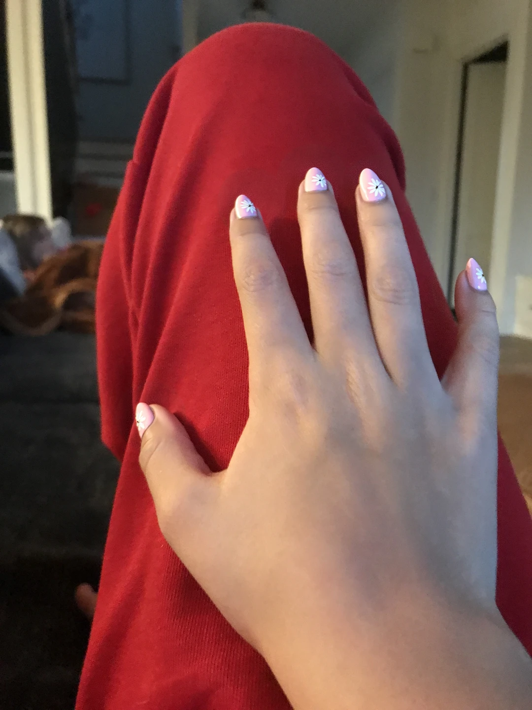 Elegant oval nails are coated in a soft pastel pink, creating a delicate and romantic base. On the ring fingers, a minimalistic white floral design is painted softly, featuring up to four tiny blossoms with thin, flowing stems, ensuring the look remains subtle and refined. The other nails maintain the soft pink base without additional patterns, allowing the floral accents to stand out gracefully. A glossy finish adds a touch of sophistication, perfect for a summer wedding ambiance.