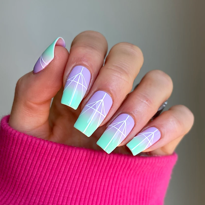 Nails featuring a pastel rainbow gradient, transitioning smoothly from soft lavender to pale mint green. The middle fingers on both hands are adorned with delicate, minimalist geometric patterns in white, featuring up to four intersecting lines that create a subtle elegance without overwhelming the aesthetic. The other nails maintain the same gradient but are kept clean and simple for balance. A glossy finish enhances the light-catching effect, making these long square nails perfectly festival-ready with a playful yet sophisticated twist.