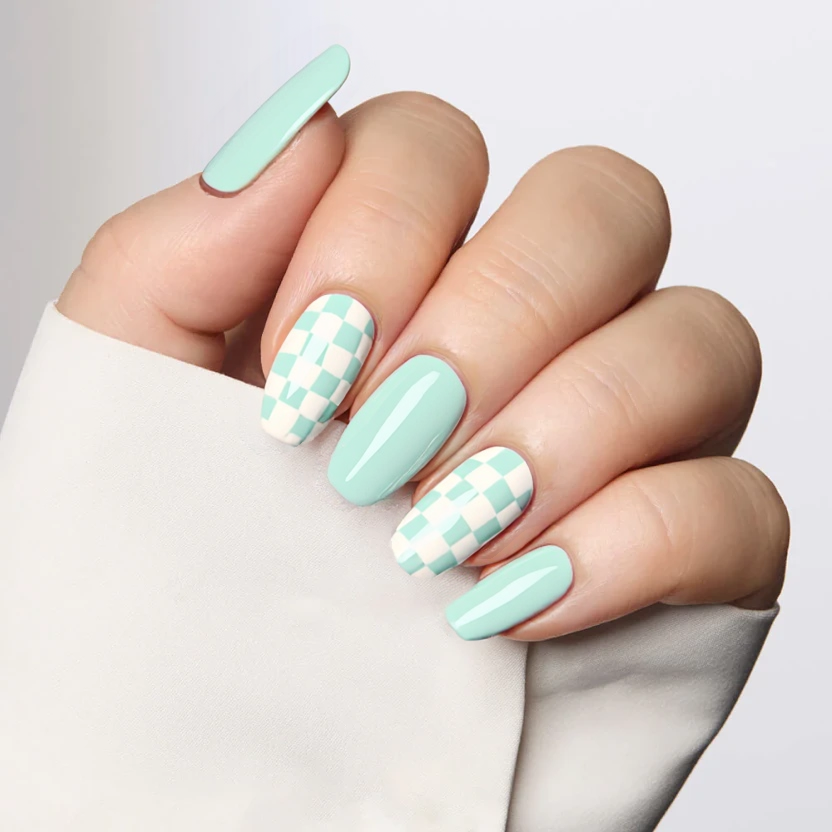 Nails featuring a soft mint gradient that transitions from a darker mint at the cuticle to a lighter shade at the tips, creating a fresh, airy effect ideal for the almond shape. The middle and ring fingers showcase a delicate chessboard pattern, alternating between crisp white and mint squares, with a subtle matte finish for an elegant touch. The gradient base on the remaining fingers complements the playful yet sophisticated chessboard design, while maintaining balance and harmony across the medium-length almond nails.